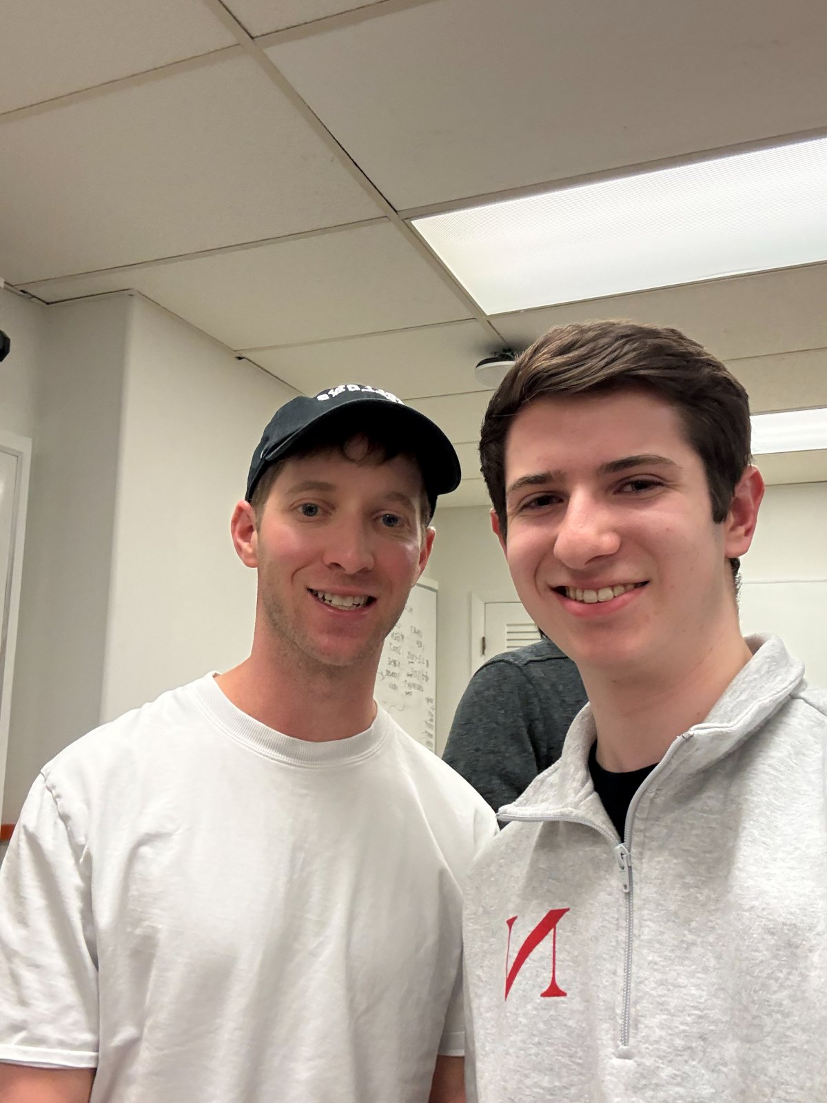 Noah standing with Cory Levy in a classroom, both smiling at the camera.